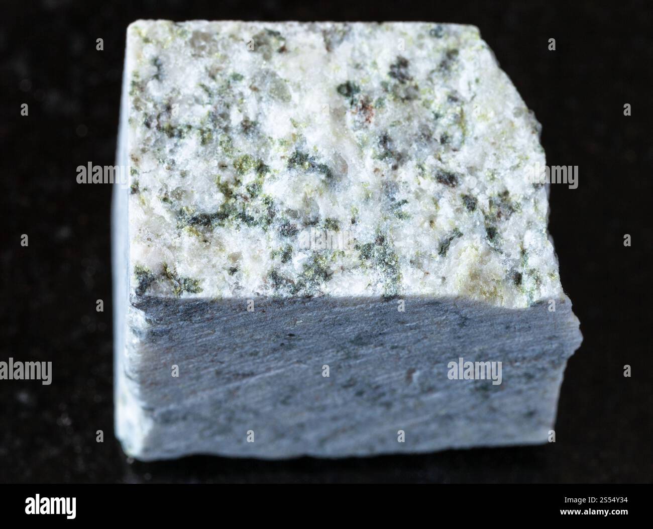 primo piano di un campione di minerale naturale proveniente dalla collezione geologica - roccia di granito bianca grezza su fondo di granito nero. Granito bianco grezzo su nero Foto Stock