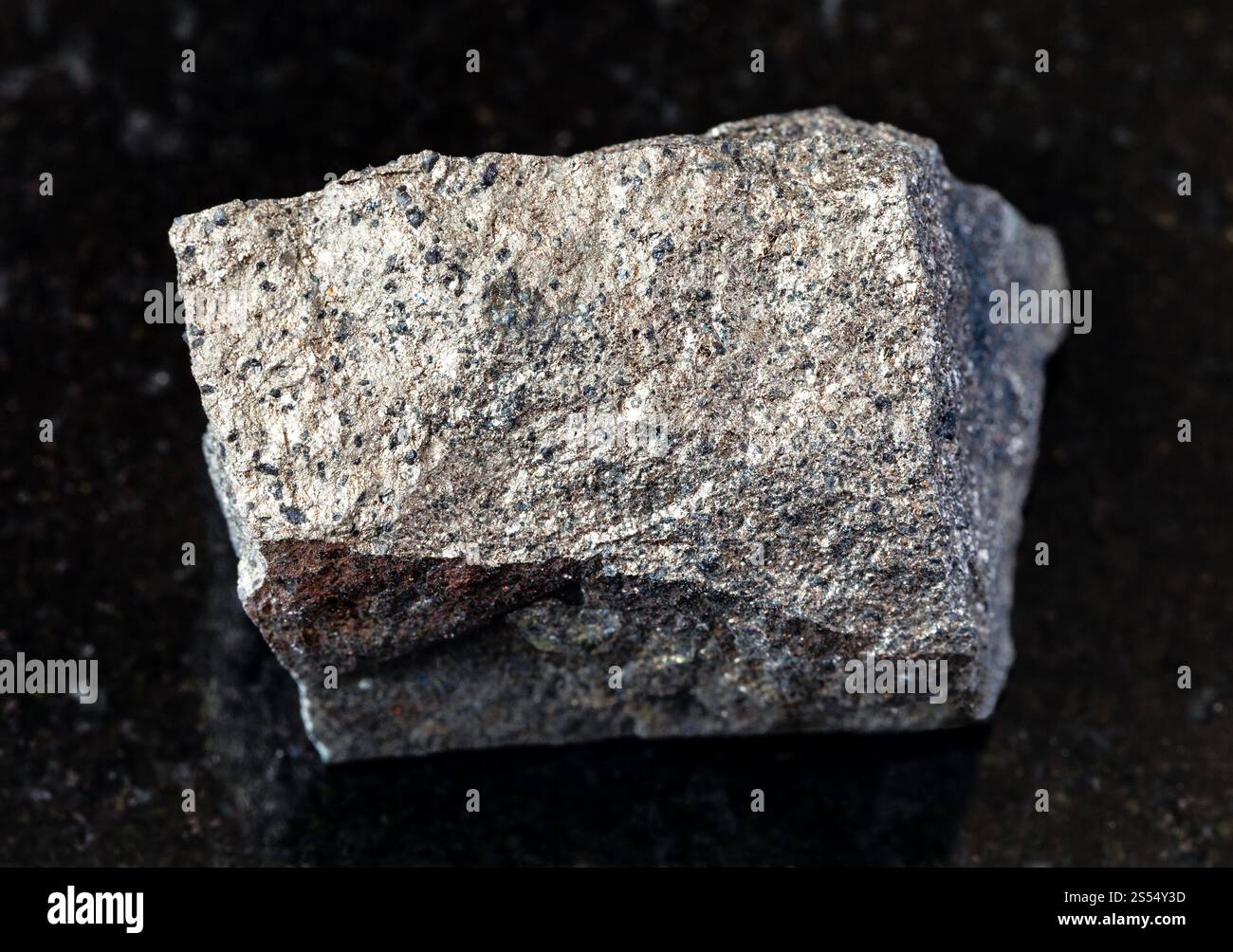primo piano di un campione di minerale naturale proveniente dalla collezione geologica - roccia di Pyrrhotite (Pyrotite) non lucidata su fondo di granito nero da Kola Foto Stock