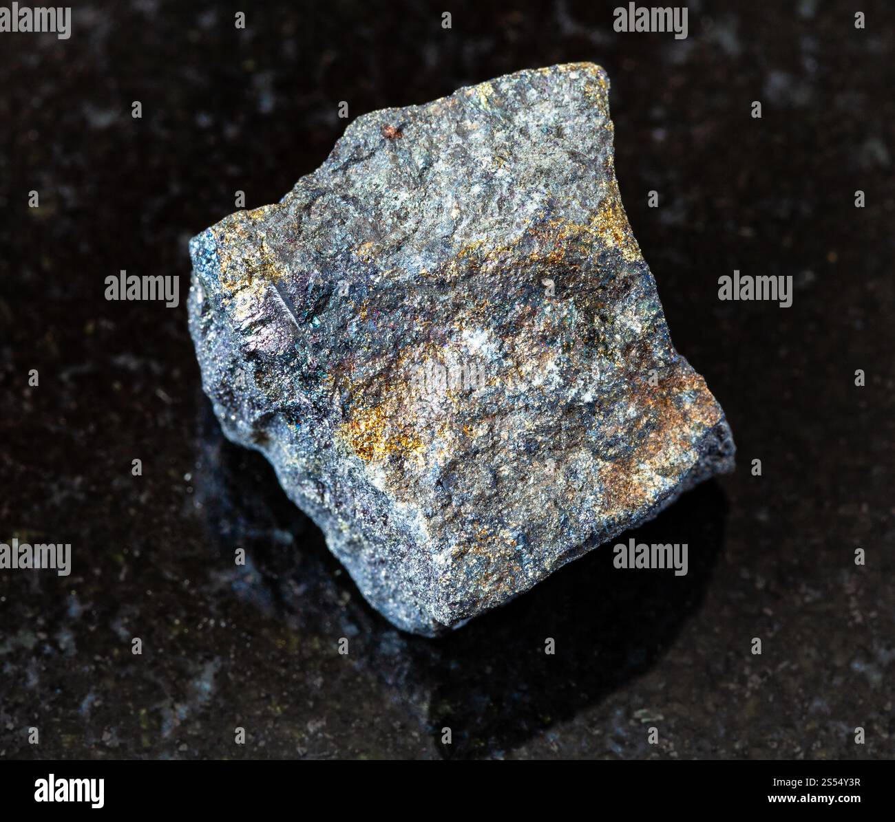primo piano di un campione di minerale naturale proveniente dalla collezione geologica - Bornite ruvida con roccia calcopirite su sfondo granitico nero proveniente dall'Azerbaigian. Foto Stock