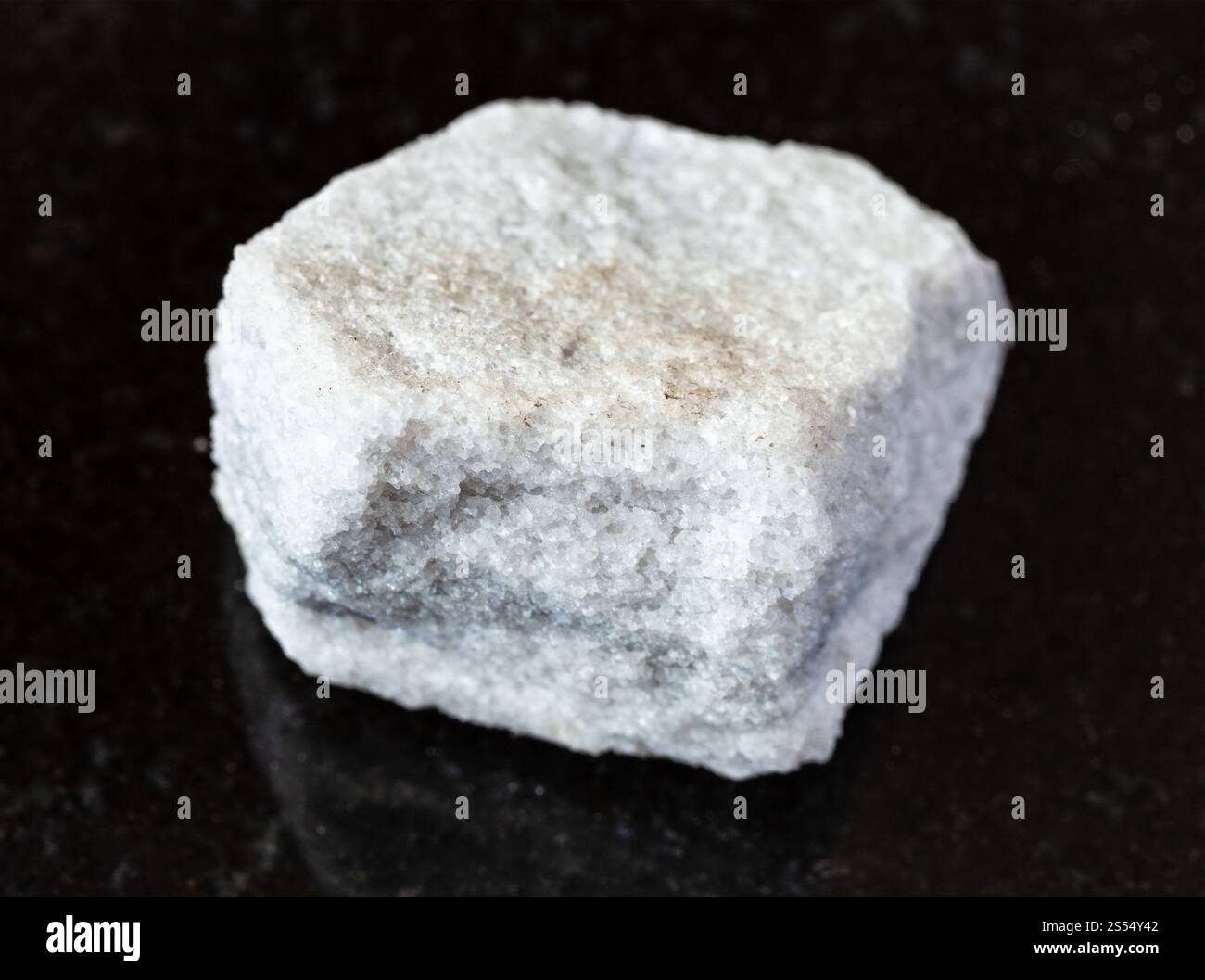 primo piano di un campione di minerale naturale proveniente dalla collezione geologica - pietra di marmo non lucidata su sfondo di granito nero proveniente dalla regione di Mosca, Russia. Foto Stock