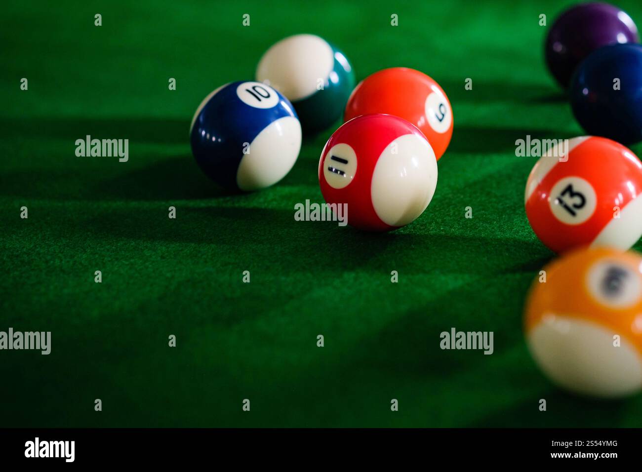 Mans mano e braccio cue giocano a biliardo o si preparano a sparare palle da biliardo su un tavolo da biliardo verde. Palline da biliardo colorate sul fregio verde Foto Stock