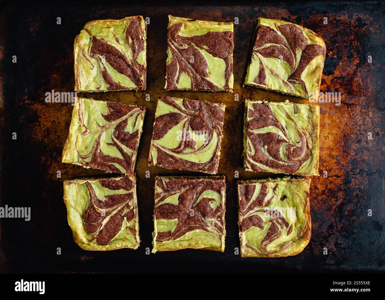 Brownie Matcha Cheesecake su una teglia rustica: Brownie con formaggio cremoso di tè verde tagliati a quadrati su una teglia da forno vintage Foto Stock