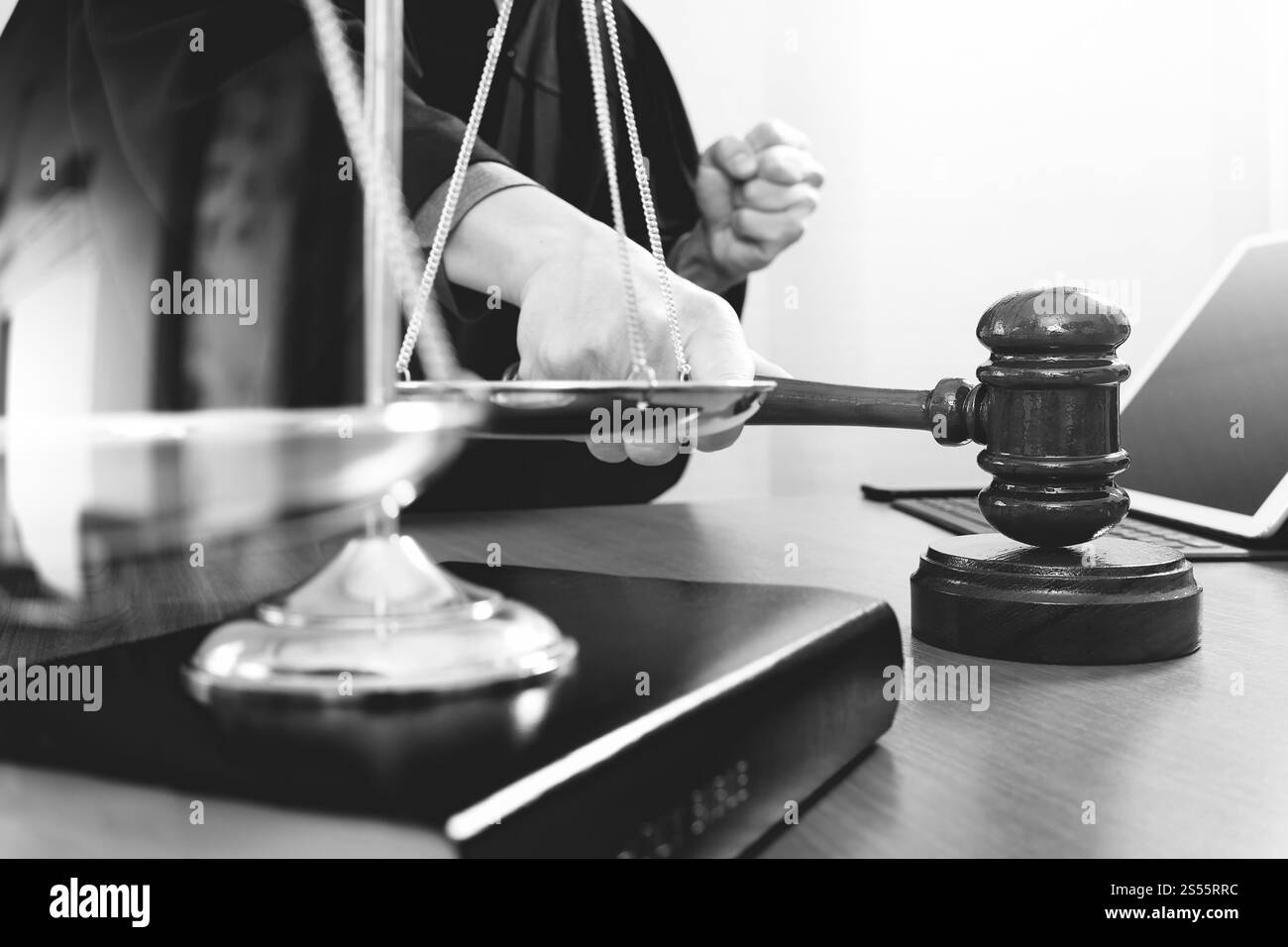 concetto di giustizia e diritto. Giudice maschile in un'aula di tribunale con il martelletto, che lavora con smartphone e tablet digitali con scala di ottone su legno Foto Stock