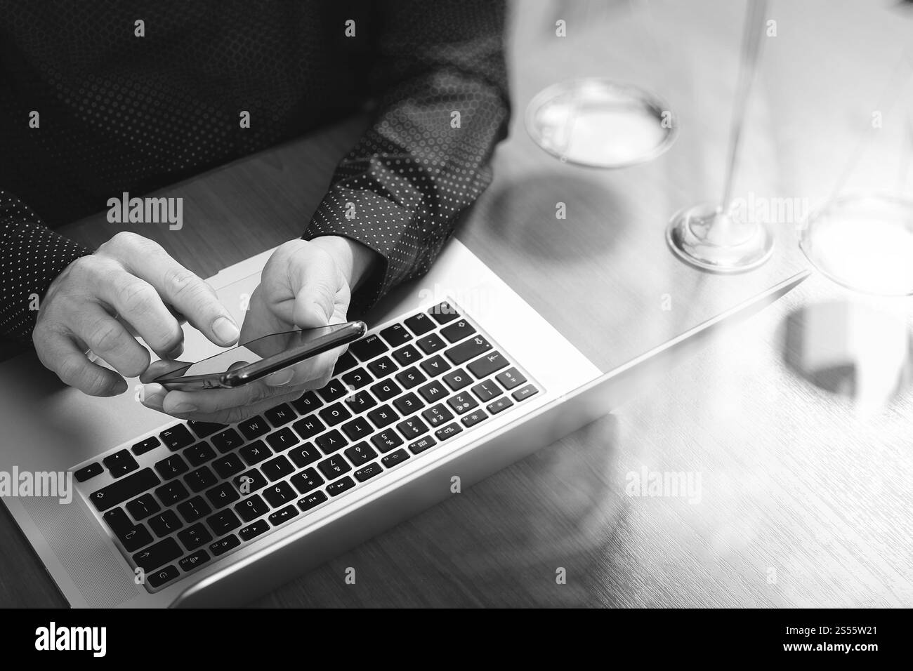 concetto di giustizia e diritto. Avvocato maschile in ufficio con il martelletto, lavorare con smartphone, tablet digitale computer docking tastiera, bilancia in ottone, su legno Foto Stock