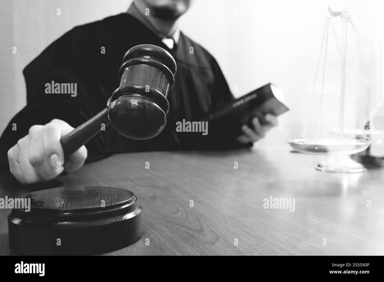 La giustizia e la nozione di diritto.Giudice maschi nelle aule di un tribunale con il martello e lavoro con il libro sacro e scala di ottone su tavola di legno,in bianco e nero Foto Stock