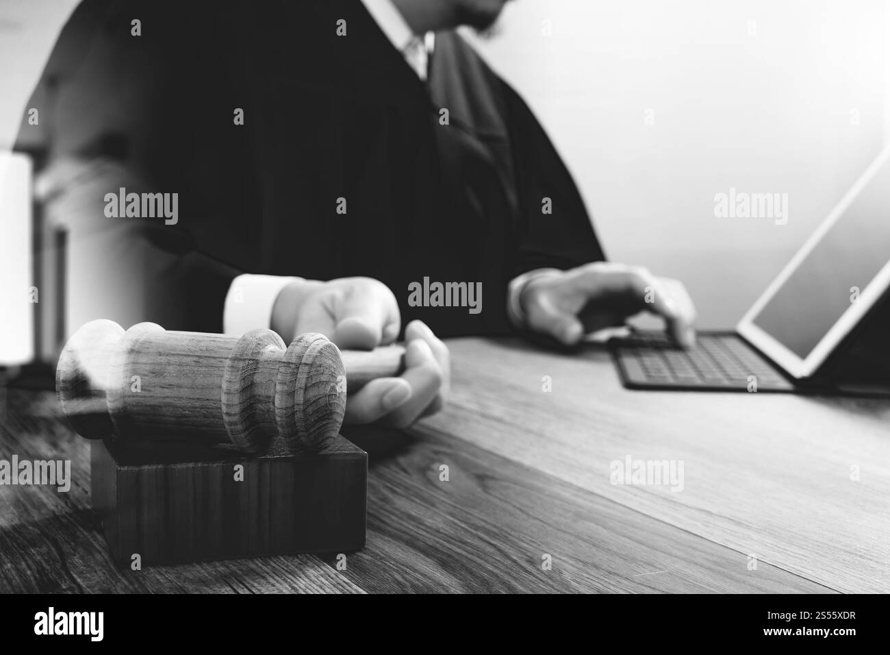 concetto di giustizia e diritto. Giudice maschile in un'aula con il martelletto, che lavora con lo smartphone, tablet digitale, tastiera docking su legno Foto Stock