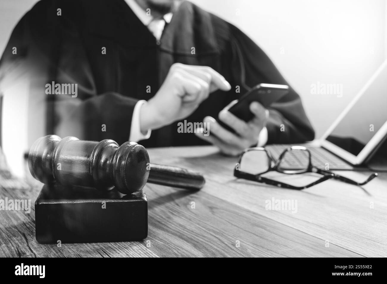 concetto di giustizia e diritto. Giudice maschile in un'aula con il martelletto, che lavora con lo smartphone, tablet digitale, tastiera docking su legno Foto Stock