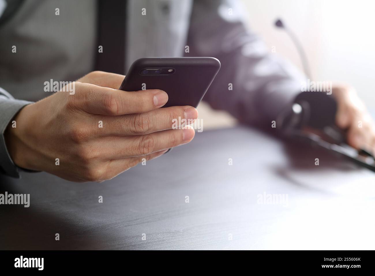 Imprenditore tramite VOIP auricolare con il telefono cellulare e il concetto di comunicazione centro di chiamata sulla scrivania in legno Foto Stock