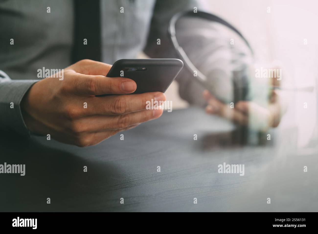 Imprenditore tramite VOIP auricolare con il telefono cellulare e il concetto di comunicazione centro di chiamata sulla scrivania in legno Foto Stock