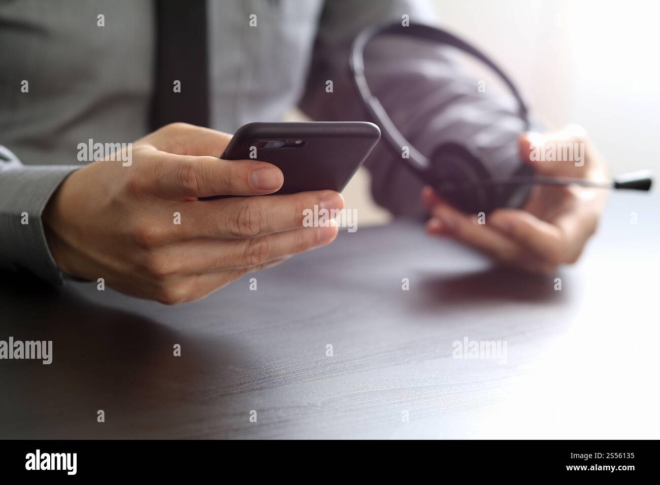 Imprenditore tramite VOIP auricolare con il telefono cellulare e il concetto di comunicazione centro di chiamata sulla scrivania in legno Foto Stock