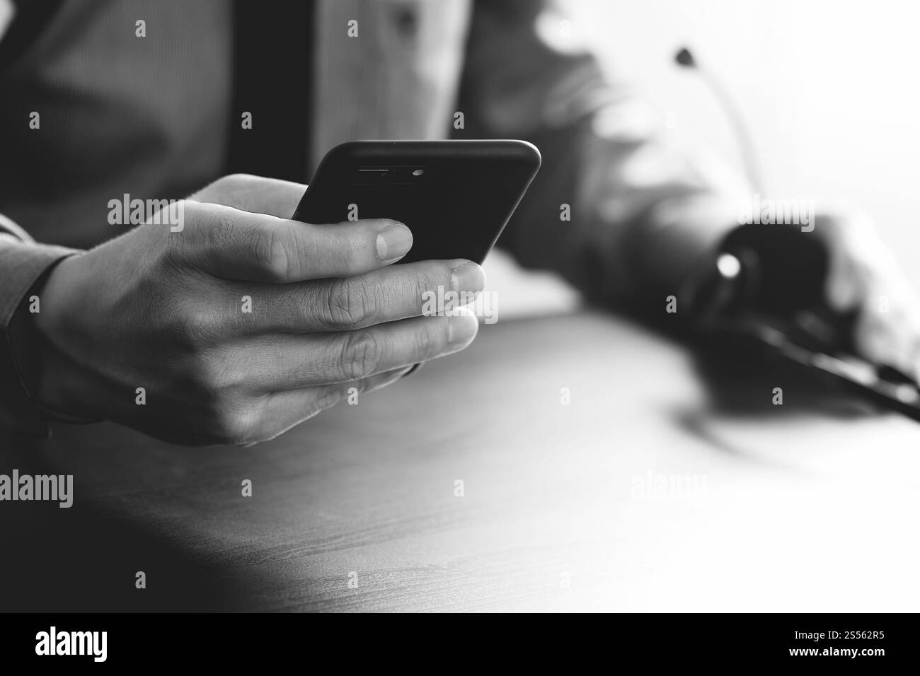 Imprenditore tramite VOIP auricolare con il telefono cellulare e il concetto di comunicazione centro di chiamata sulla scrivania in legno,in bianco e nero Foto Stock
