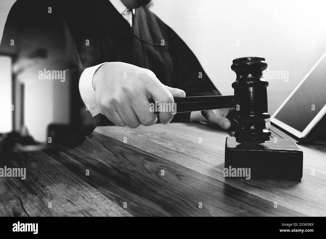 concetto di giustizia e diritto. Giudice maschile in un'aula di tribunale che colpisce il martelletto, lavora con tablet digitale computer docking tastiera su tavolo di legno, nero e. Foto Stock