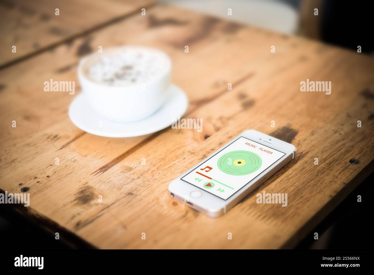 Smartphone con il lettore musicale sulla schermata. Scrivania in legno e caffè presso il cafe. Foto Stock
