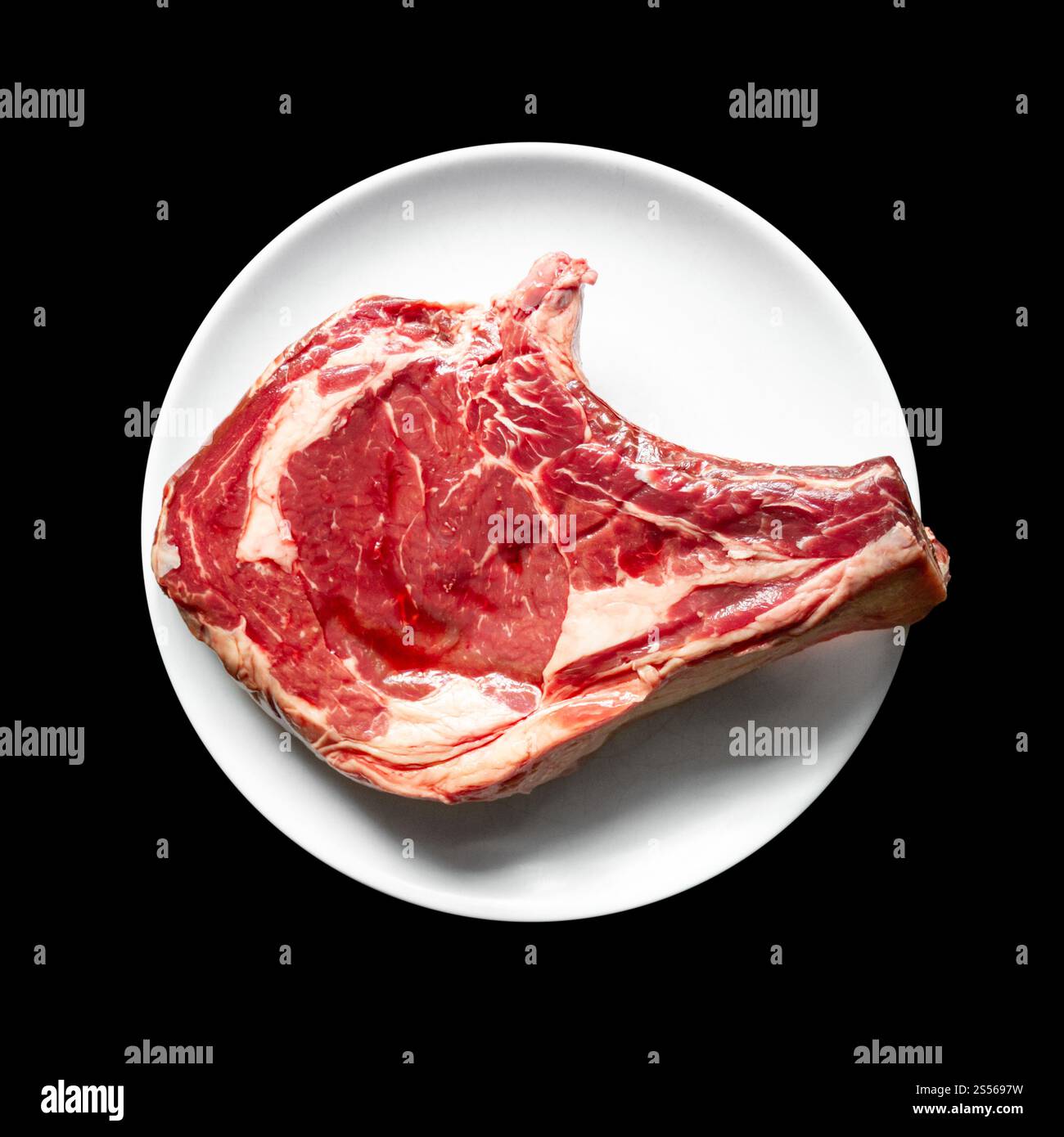 Costolette di manzo crude su un piatto isolato su sfondo nero. Vista dall'alto. Costolette di manzo su un piatto isolato sul nero Foto Stock