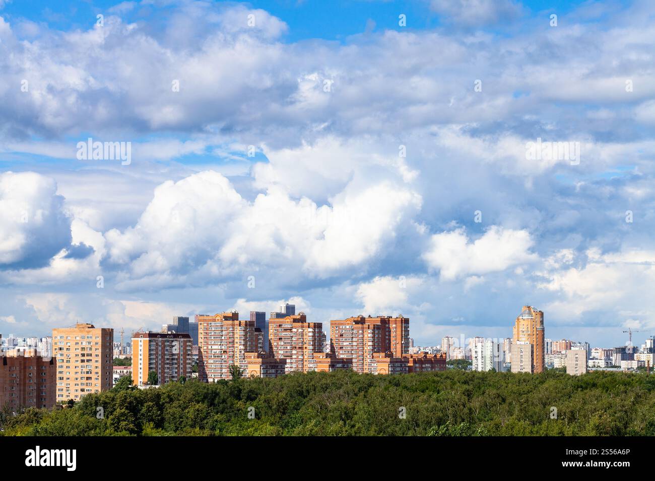 grandi nuvole bianche nel cielo azzurro sopra appartamenti case e verde parco urbano in città nelle soleggiate giornate estive. grandi nuvole bianche sulla città e sul parco in estate Foto Stock