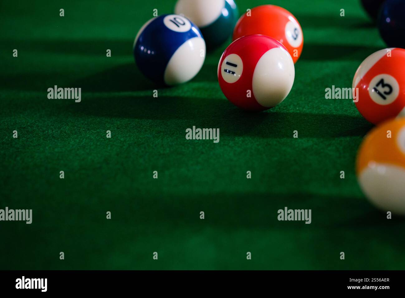 Mans mano e braccio cue giocano a biliardo o si preparano a sparare palle da biliardo su un tavolo da biliardo verde. Palline da biliardo colorate sul fregio verde Foto Stock