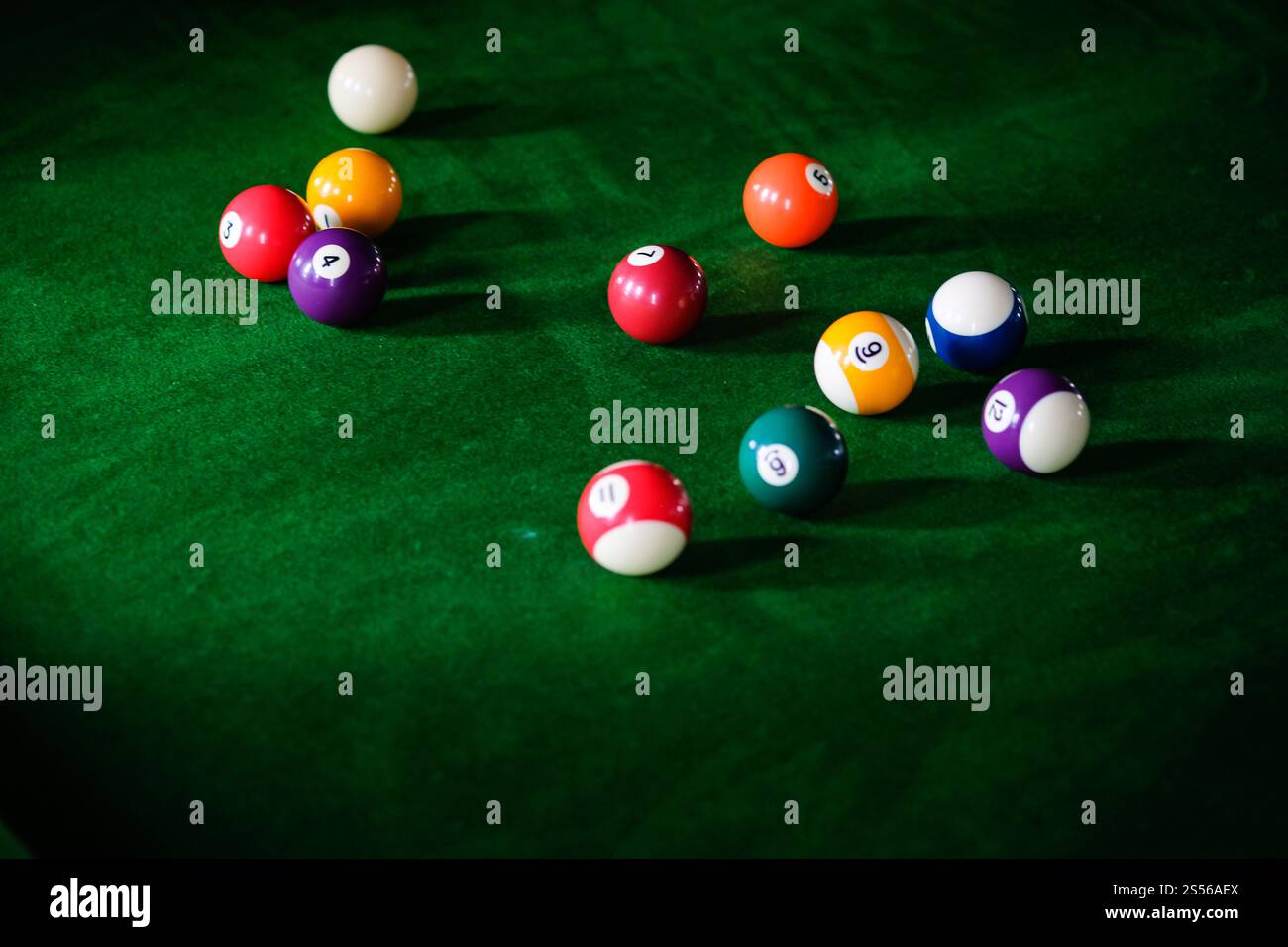 Mans mano e braccio cue giocano a biliardo o si preparano a sparare palle da biliardo su un tavolo da biliardo verde. Palline da biliardo colorate sul fregio verde Foto Stock