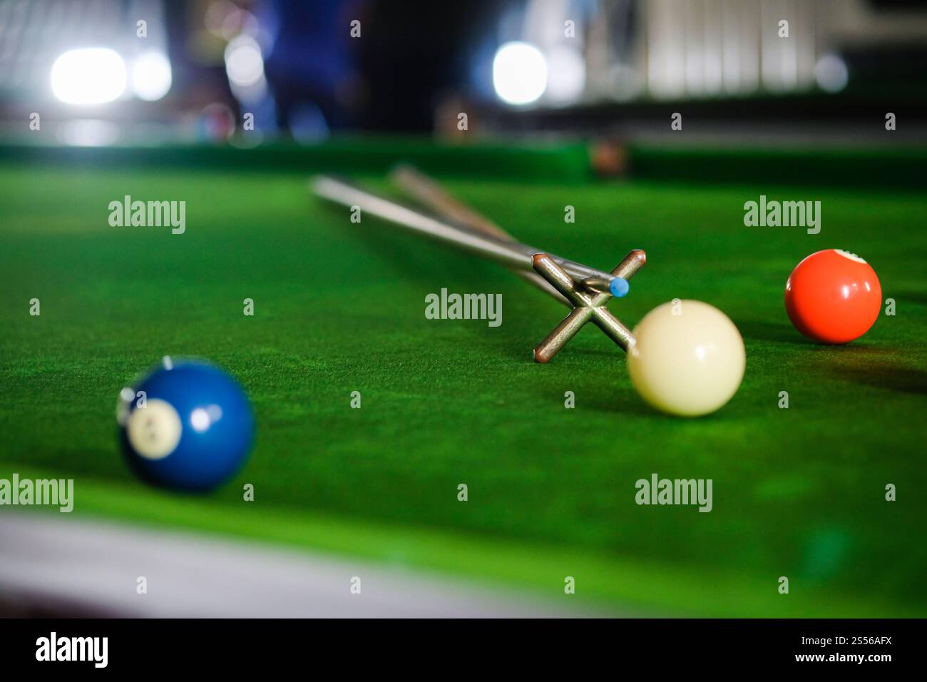 Mans mano e braccio cue giocano a biliardo o si preparano a sparare palle da biliardo su un tavolo da biliardo verde. Palline da biliardo colorate sul fregio verde Foto Stock