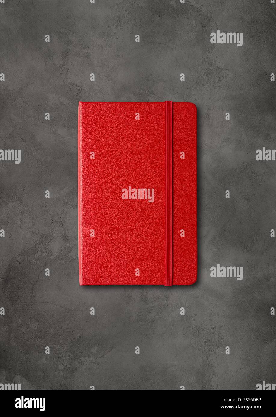 Mockup di notebook chiuso rosso isolato su sfondo di cemento scuro. Taccuino chiuso rosso su sfondo di cemento scuro Foto Stock