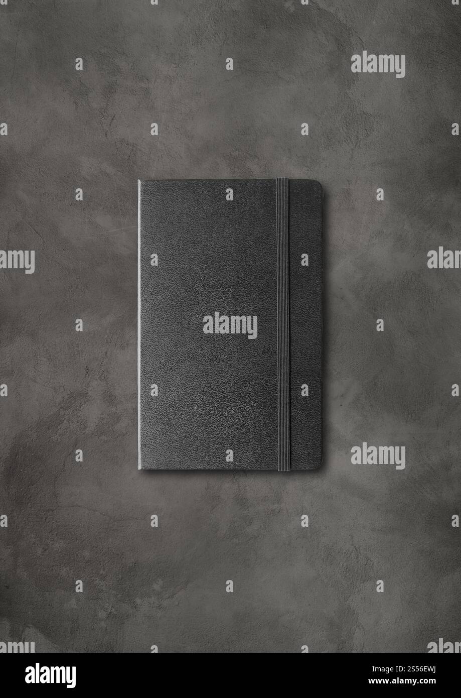 Mockup di notebook chiuso nero isolato su sfondo di cemento scuro. Notebook chiuso nero su sfondo di cemento scuro Foto Stock