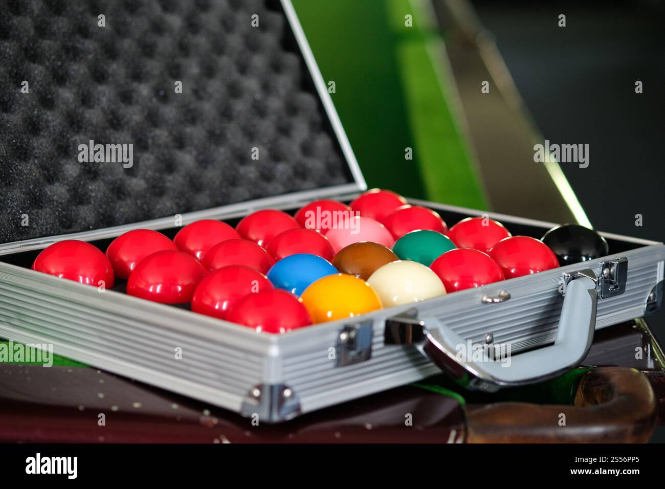 Mans mano e braccio cue giocano a biliardo o si preparano a sparare palle da biliardo su un tavolo da biliardo verde. Palline da biliardo colorate sul fregio verde Foto Stock