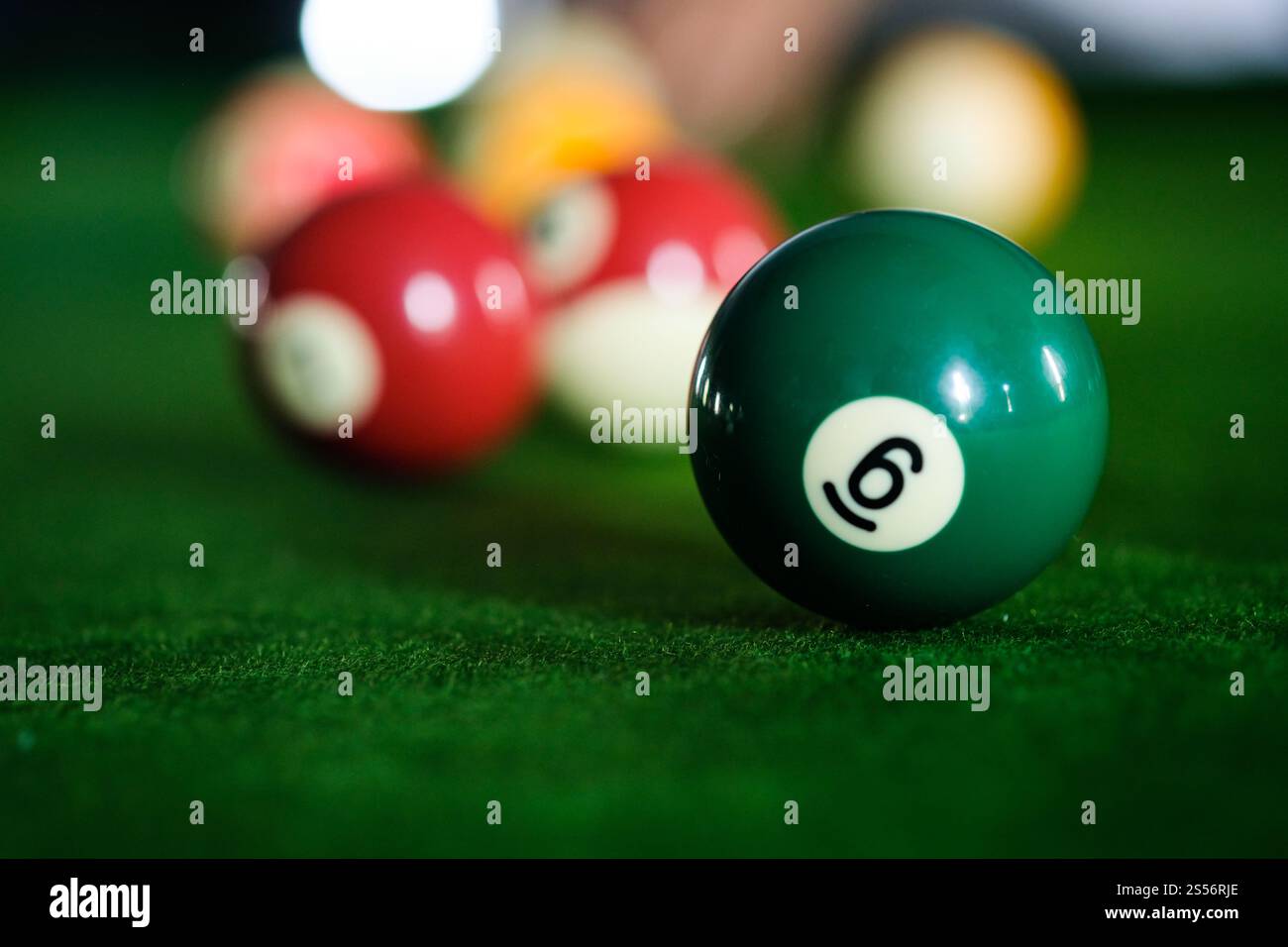 Mans mano e braccio cue giocano a biliardo o si preparano a sparare palle da biliardo su un tavolo da biliardo verde. Palline da biliardo colorate sul fregio verde Foto Stock