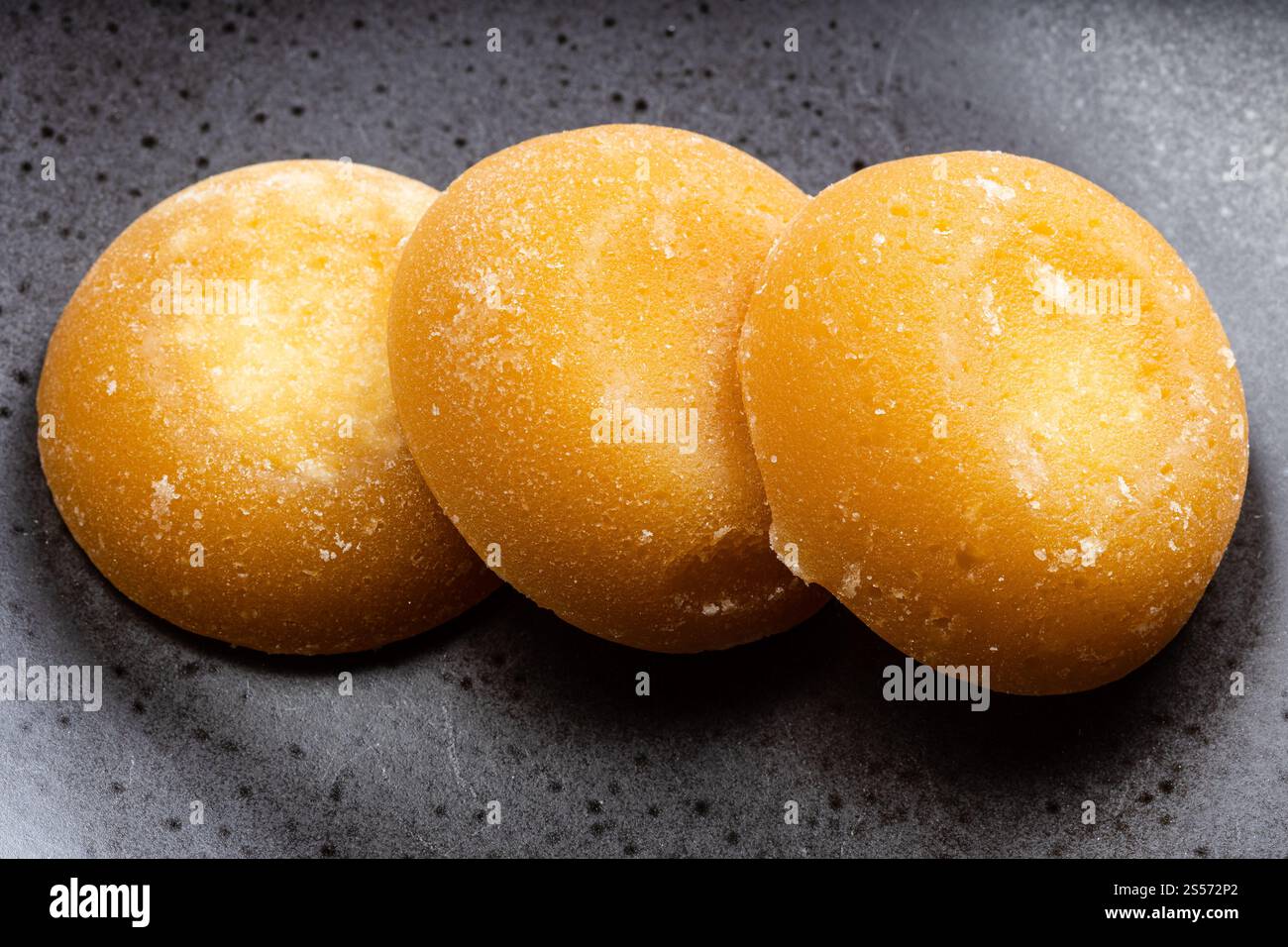 pochi pezzi interi rotondi di zucchero di palma su ceramica nera piastra Foto Stock