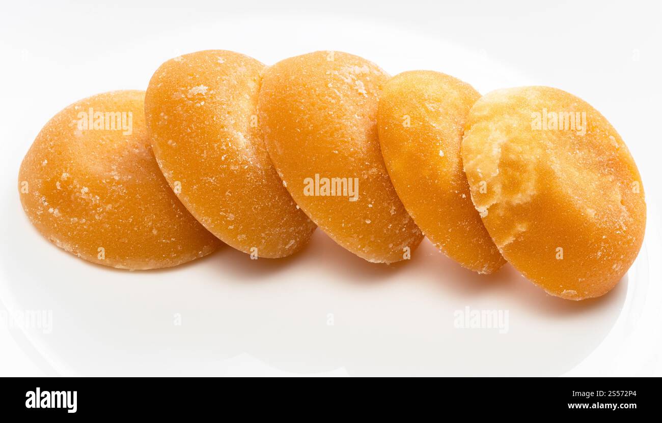 diversi pezzi rotondi interi di zucchero di palma su ceramica grigia piastra Foto Stock
