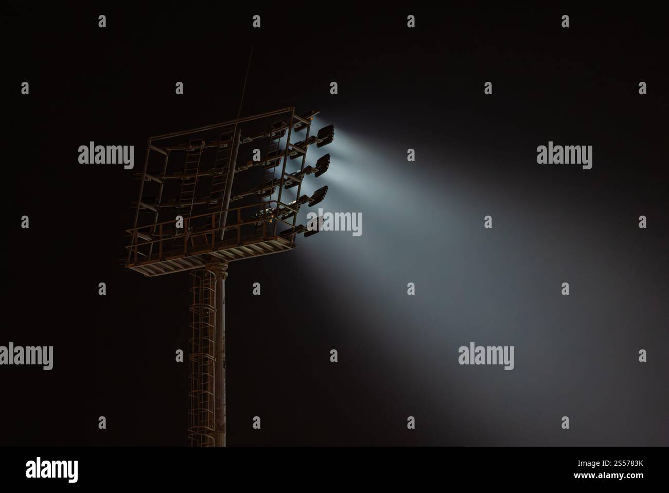 Potenti luci da stadio illuminano il cielo notturno, proiettando fasci di luce nell'oscurità, creando una scena drammatica e suggestiva Foto Stock