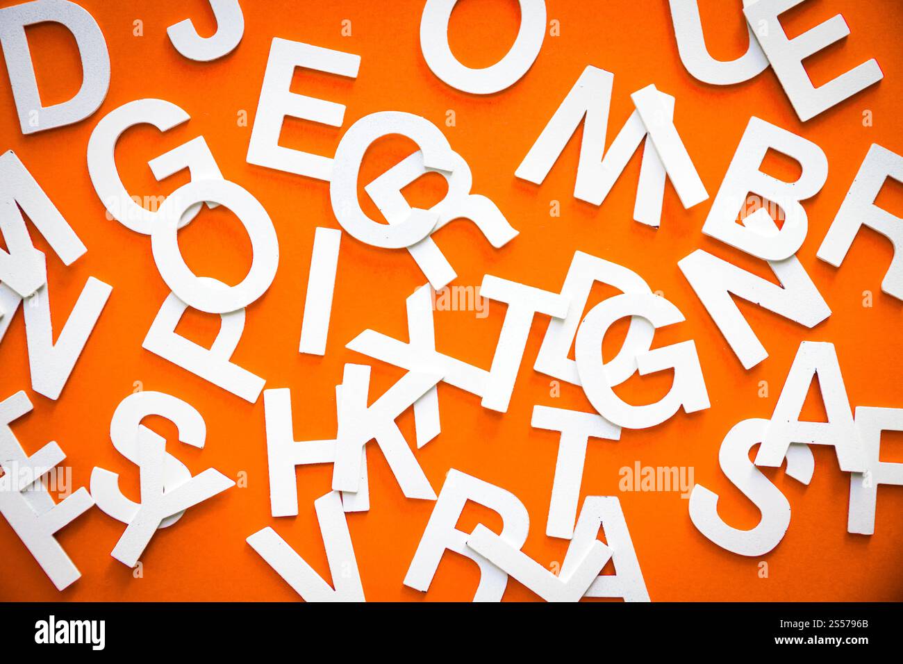 Foto vista dall'alto con lettere pila pila pila di lettere pila Concetto educativo su sfondo arancione. Foto vista dall'alto pile di lettere miste. Sfondo arancione Foto Stock