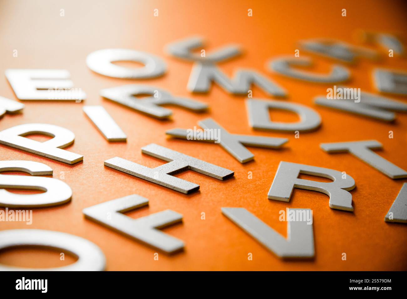 Vista ravvicinata di una pila di lettere piene miste. Concetto educativo su sfondo arancione. Vista ravvicinata pile di lettere miste. Sfondo arancione Foto Stock
