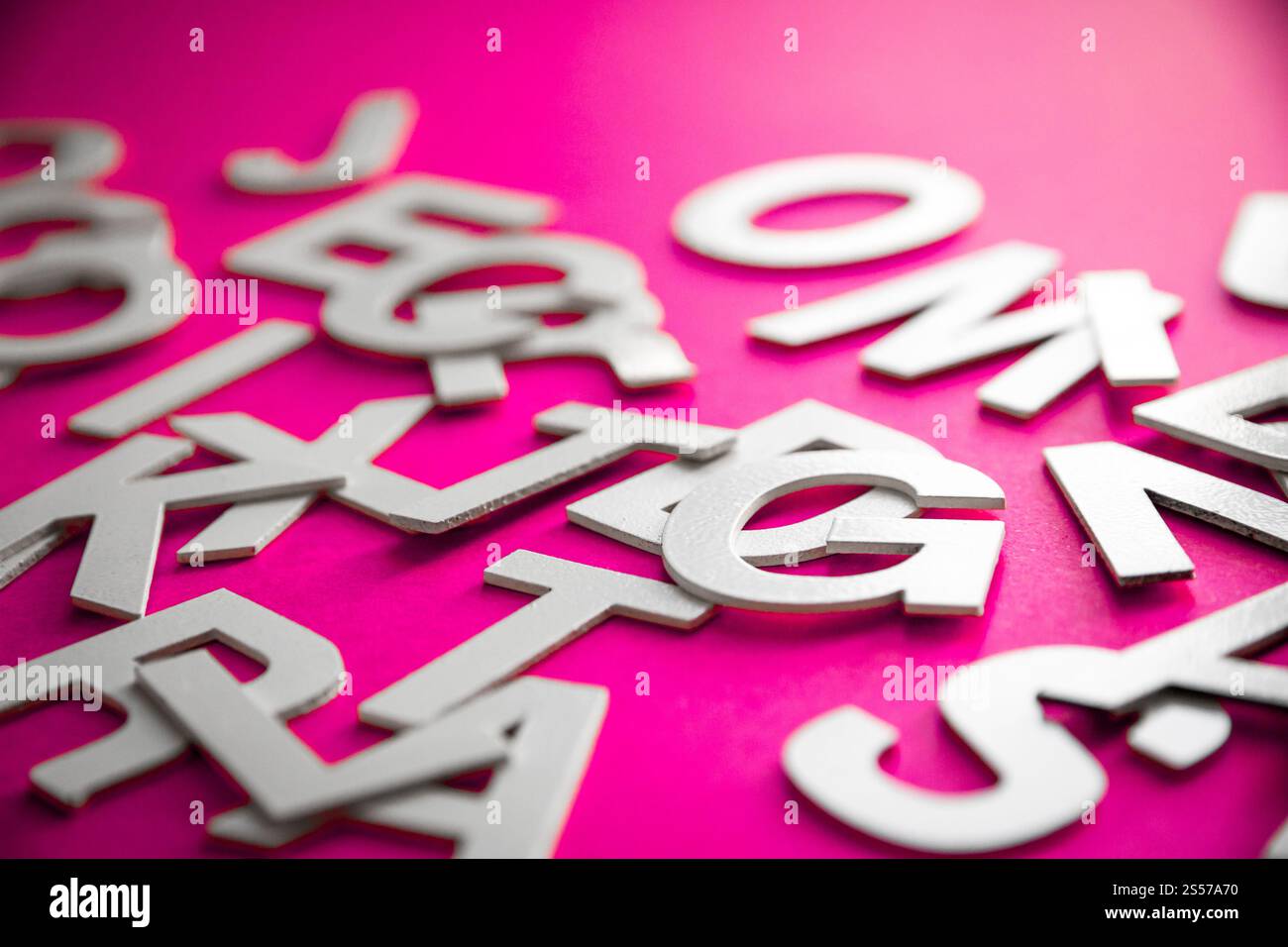 Vista ravvicinata di una pila di lettere piene miste. Concetto educativo su sfondo rosa. Foto ravvicinata con lettere miste. Sfondo rosa Foto Stock