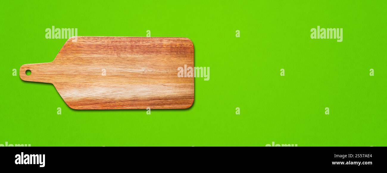 Tagliere in legno isolato su sfondo verde. Striscione orizzontale. Tagliere in legno isolato su verde. Striscione orizzontale Foto Stock