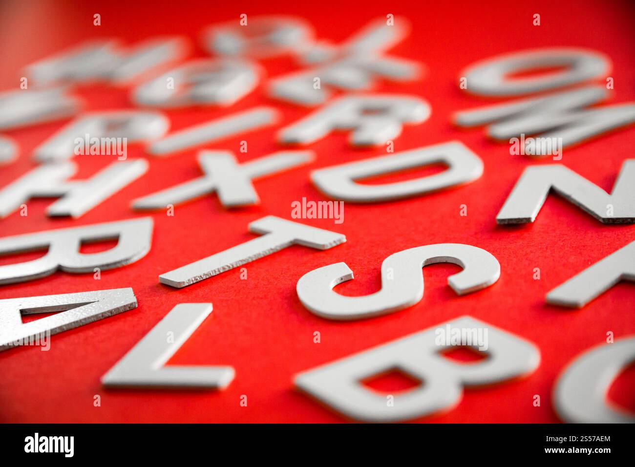 Vista ravvicinata di una pila di lettere piene miste. Concetto educativo su sfondo rosso. Foto ravvicinata con lettere miste. Sfondo rosso Foto Stock