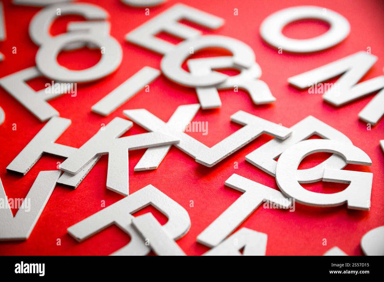 Vista ravvicinata di una pila di lettere piene miste. Concetto educativo su sfondo rosso. Foto ravvicinata con lettere miste. Sfondo rosso Foto Stock