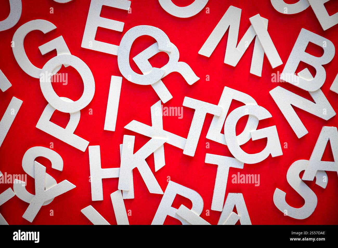 Foto vista dall'alto con lettere pila pila pila di lettere pila Concetto educativo su sfondo rosso. Foto vista dall'alto pile di lettere miste. Sfondo rosso Foto Stock