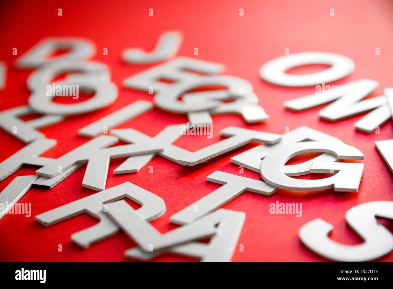 Vista ravvicinata di una pila di lettere piene miste. Concetto educativo su sfondo rosso. Foto ravvicinata con lettere miste. Sfondo rosso Foto Stock