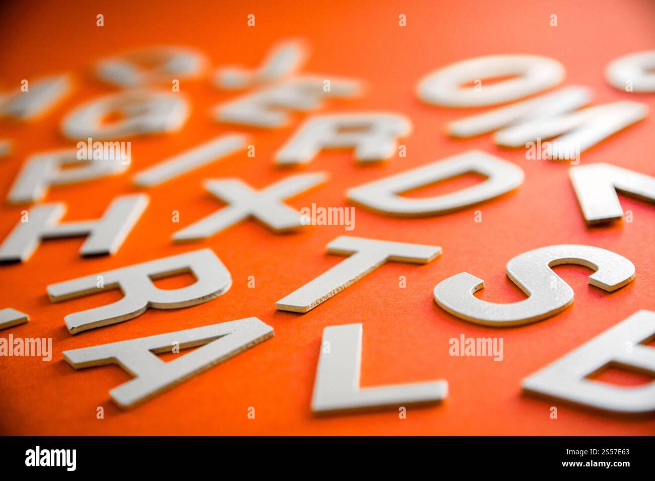 Vista ravvicinata di una pila di lettere piene miste. Concetto educativo su sfondo arancione. Vista ravvicinata pile di lettere miste. Sfondo arancione Foto Stock