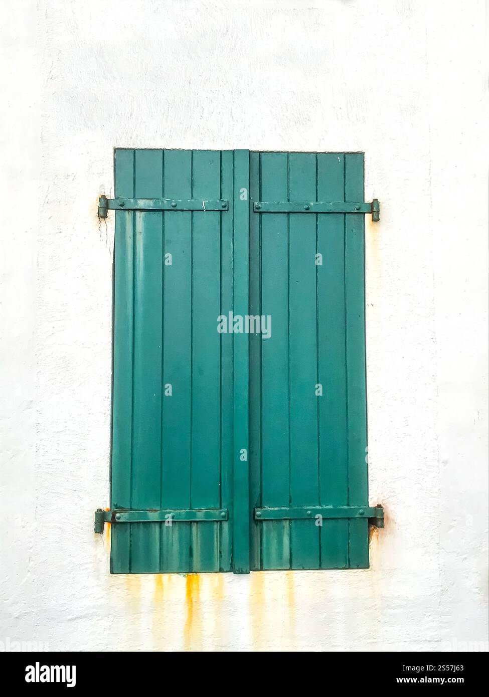 Vecchia tapparella verde in legno su una facciata di casa bianca. Vecchia tapparella verde sulla facciata di una casa bianca Foto Stock