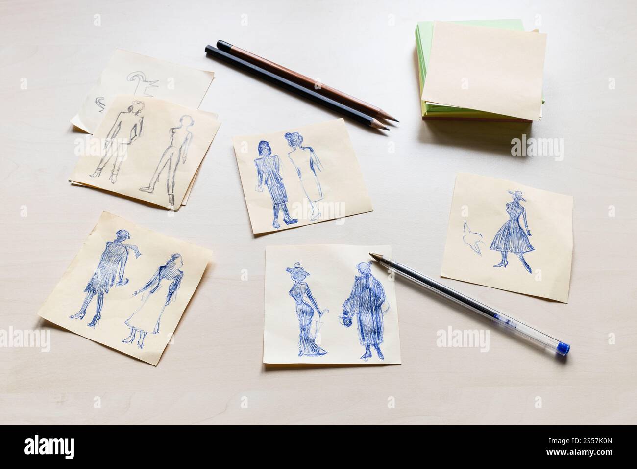 Bozzetti di silhouette alla moda di donna del XX secolo disegnati a mano su fogli di carta su tavolo marrone chiaro Foto Stock