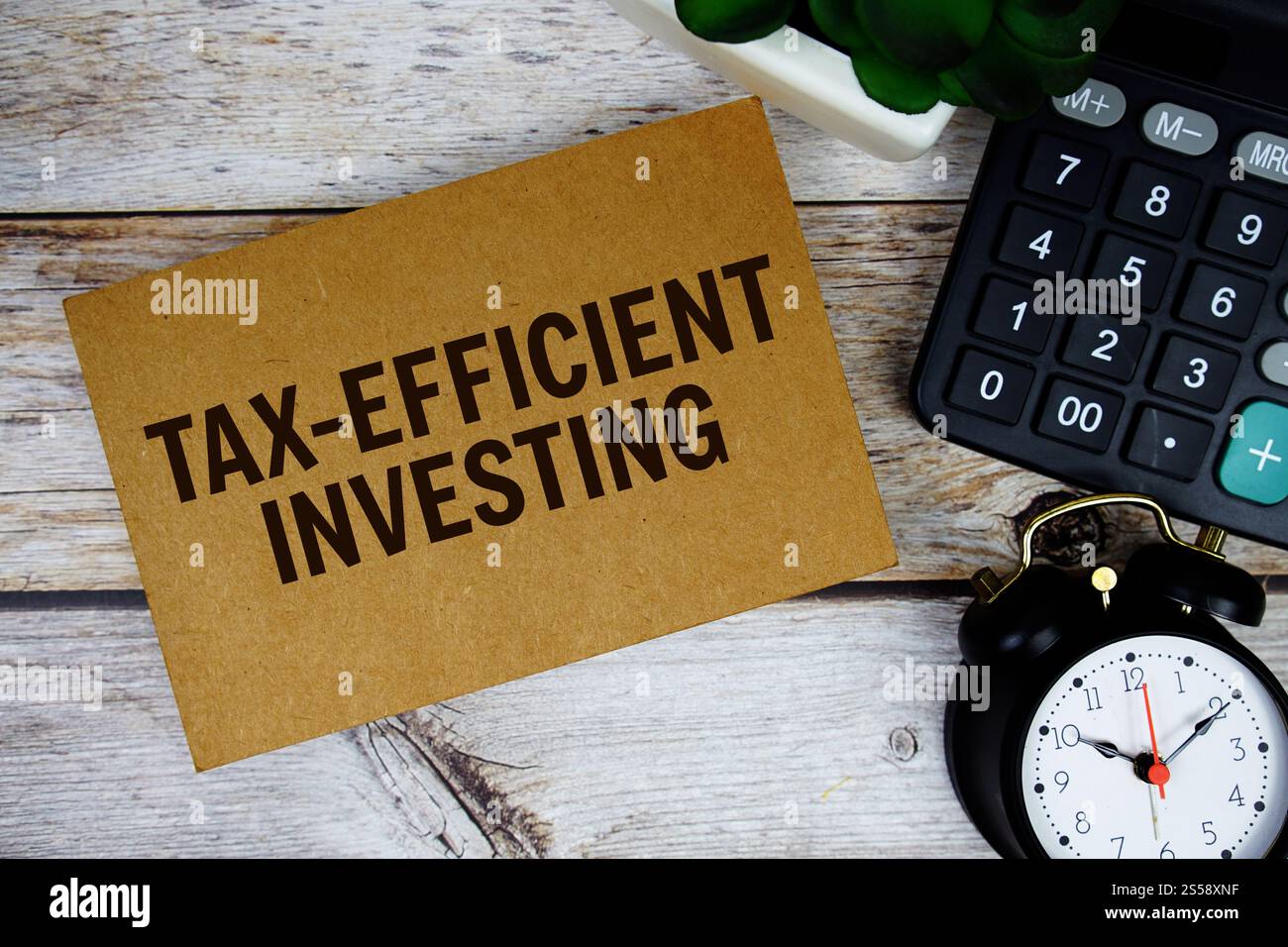 Testo di investimento efficiente sotto il profilo fiscale con sveglia e calcolatrice su sfondo in legno, Business Concept Foto Stock