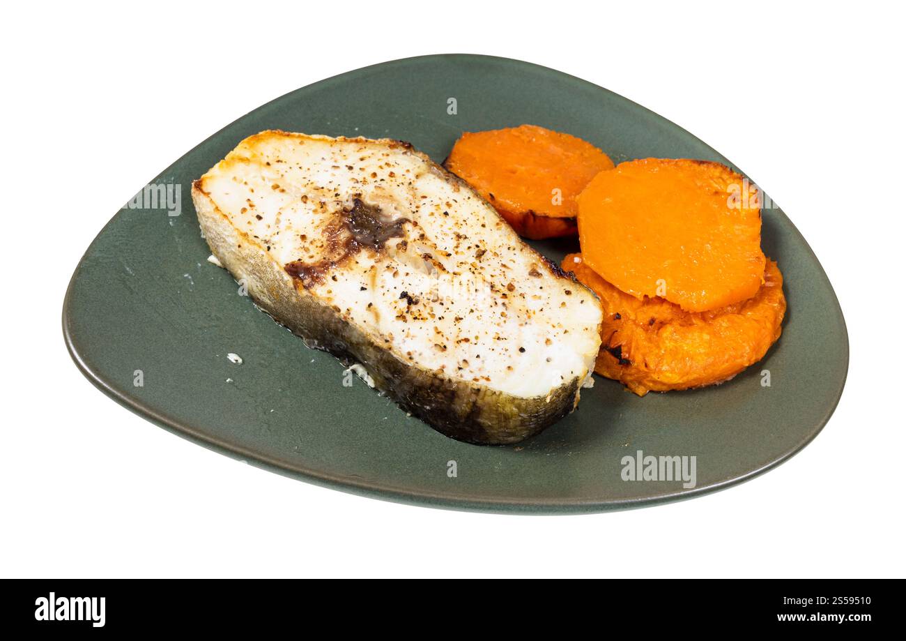 bistecca di merluzzo cotta con fette di patate dolci bollite su piatto verde isolato su sfondo bianco Foto Stock