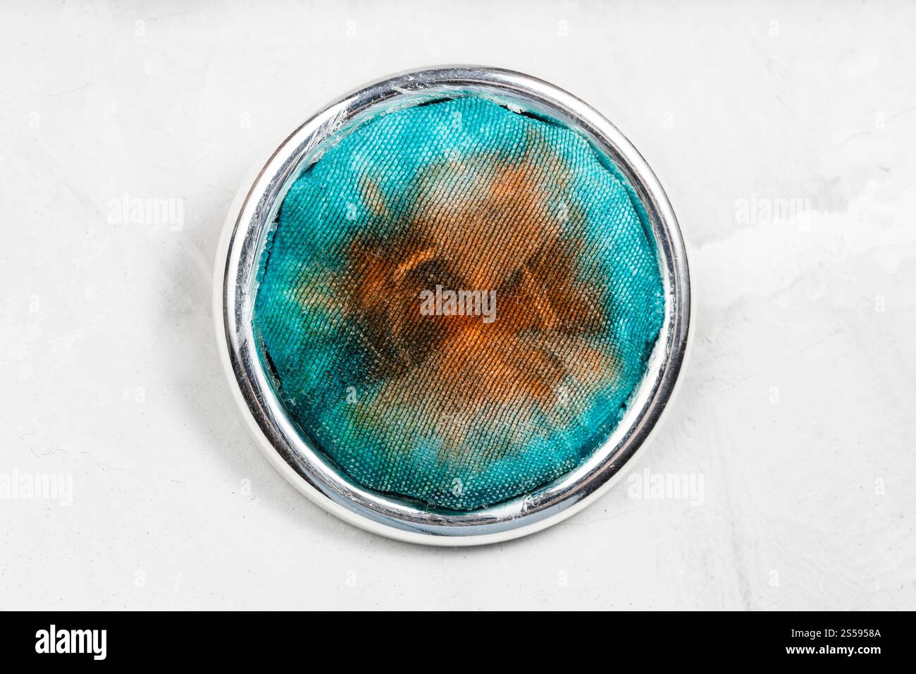 spilla rotonda in argento con inserto in seta batik tinto a mano su tavola grigia in calcestruzzo Foto Stock