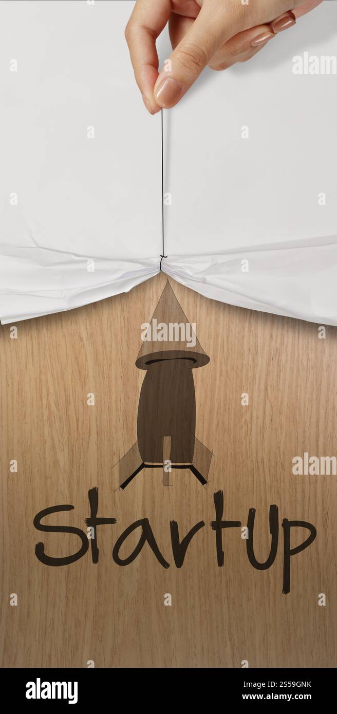 Business mano tirare la corda aprire carta stropicciata visualizza la parola start up icona word come concetto Foto Stock