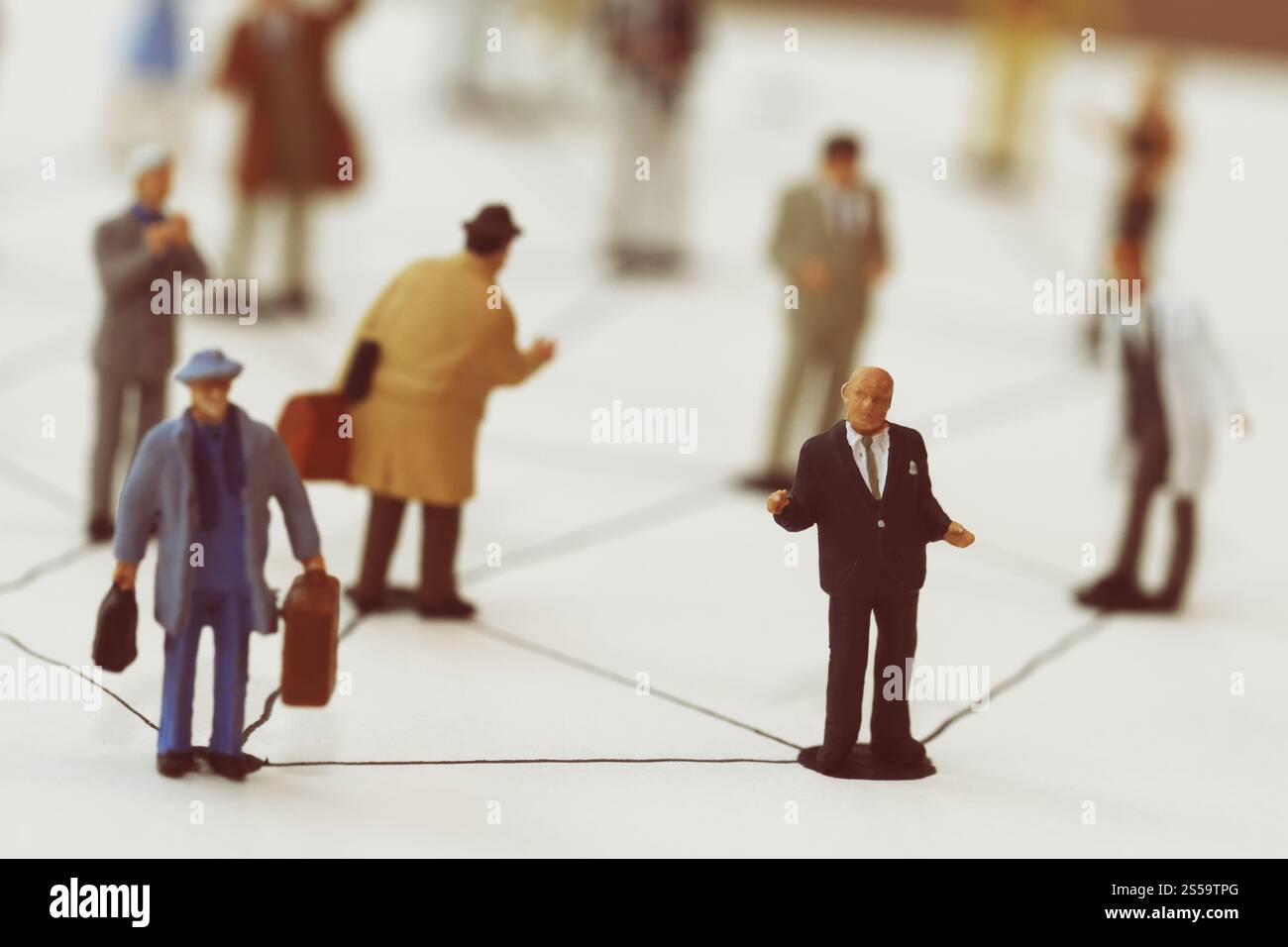 primo piano di persone in miniatura con un diagramma di social network su un notebook aperto su una scrivania in legno mentre i social media si avvicinano Foto Stock