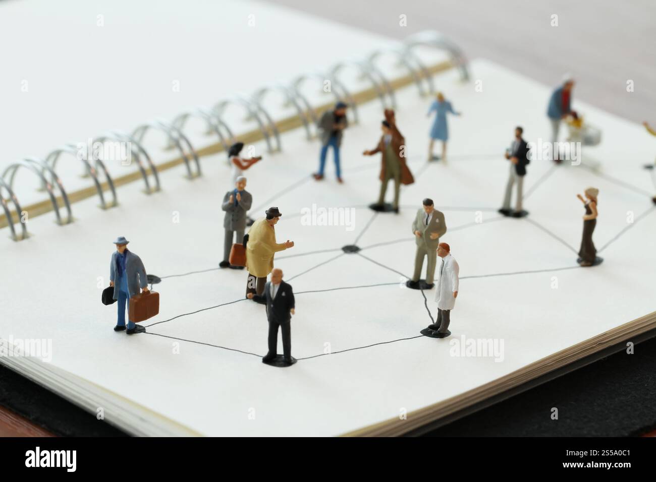 Close up di persone in miniatura con sociale schema di rete sul notebook aperto sulla scrivania di legno come i social media concept Foto Stock