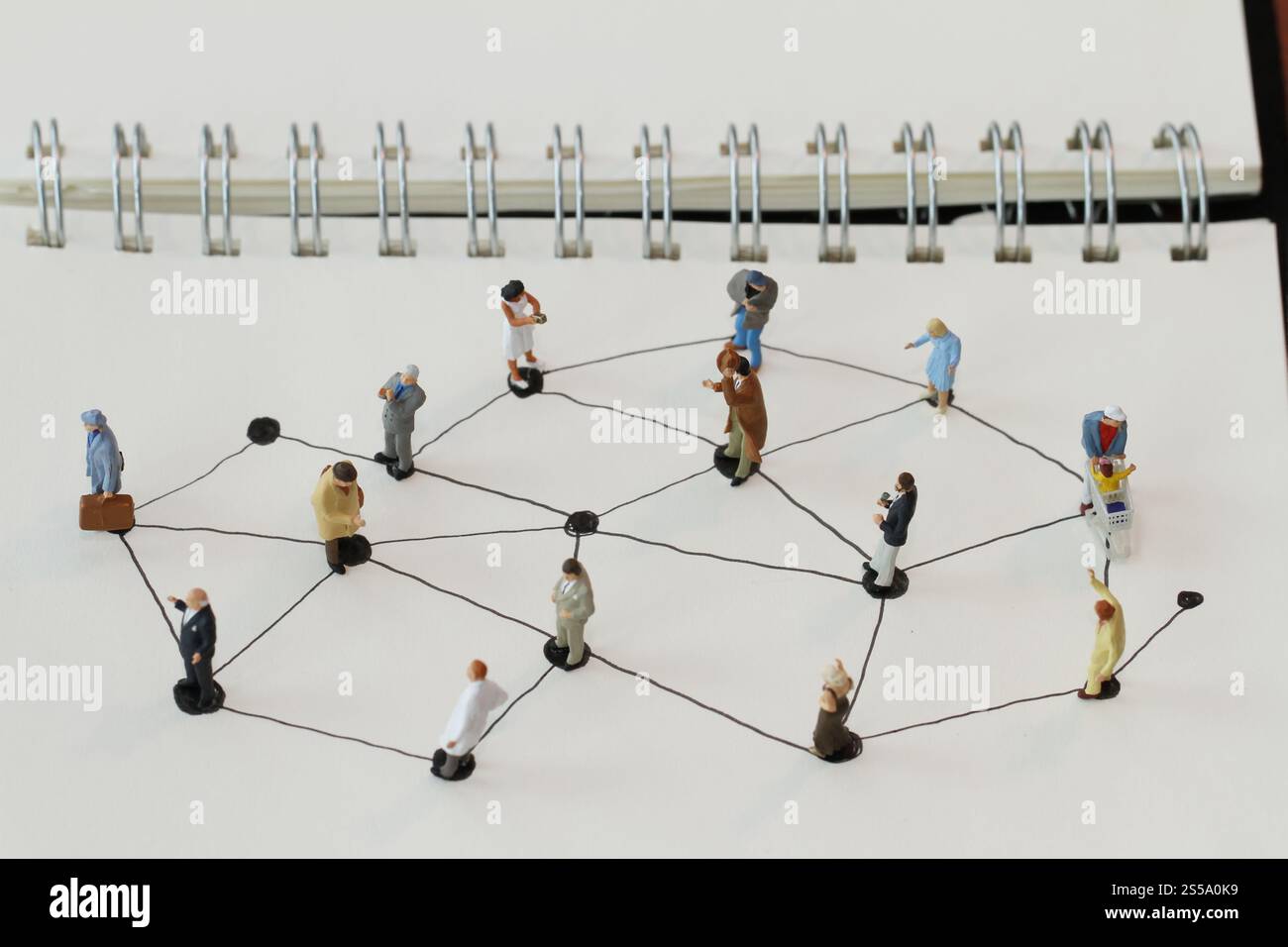 Close up di persone in miniatura con sociale schema di rete sul notebook aperto sulla scrivania di legno come i social media concept Foto Stock