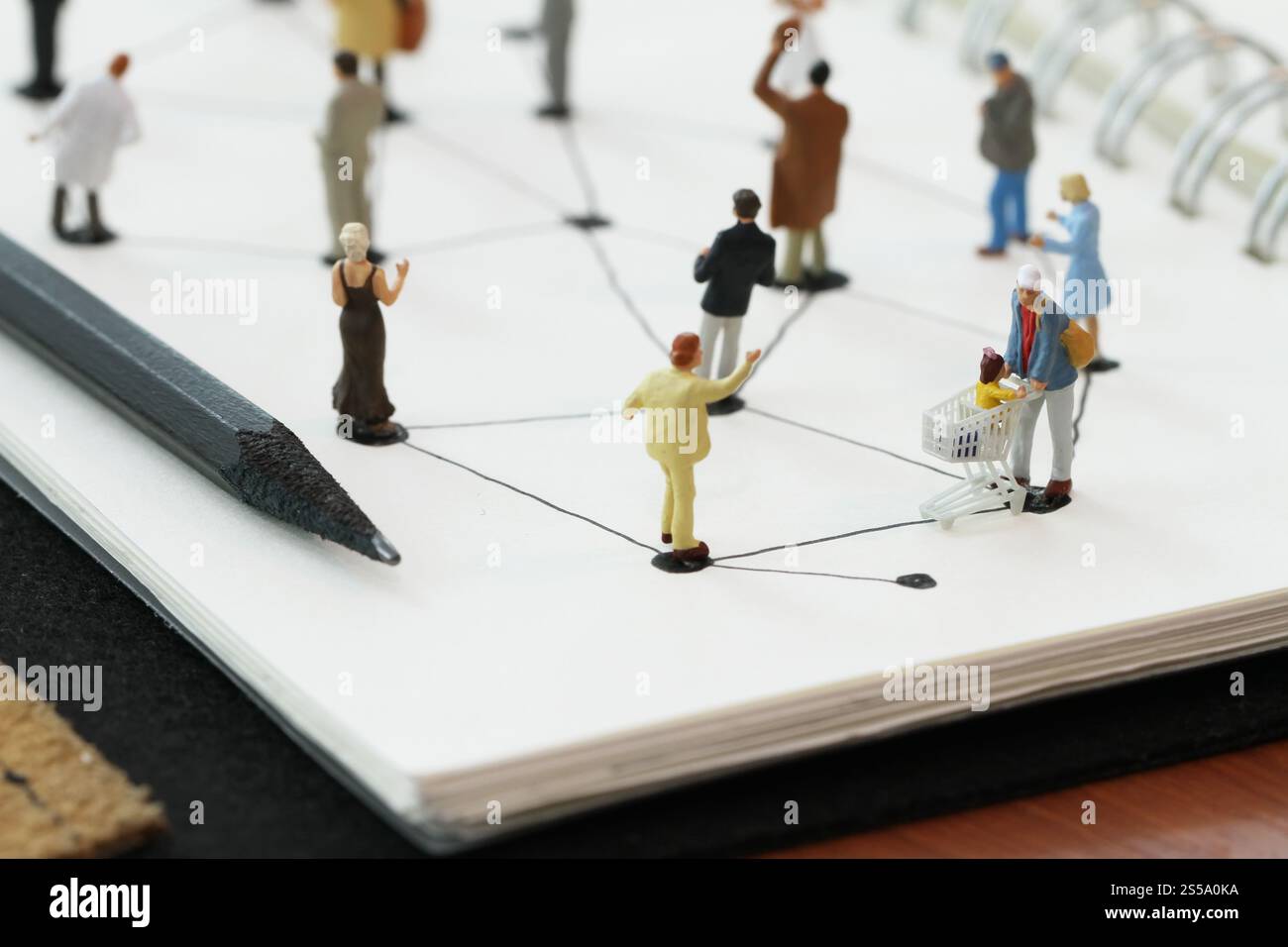 Close up di persone in miniatura con sociale schema di rete sul notebook aperto sulla scrivania di legno come i social media concept Foto Stock