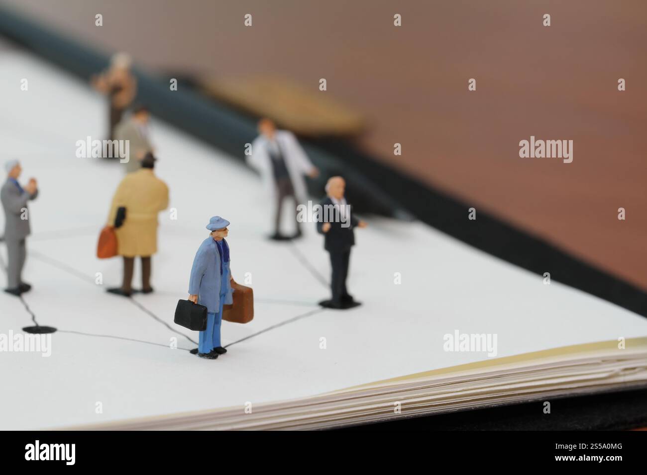 Close up di persone in miniatura con sociale schema di rete sul notebook aperto sulla scrivania di legno come i social media concept Foto Stock