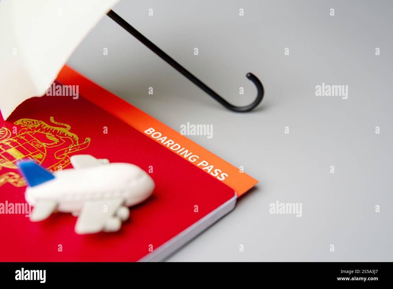 Un passaporto, una carta d'imbarco e un aeroplano giocattolo sotto un piccolo ombrello con spazio per le copie. Preparazione del viaggio, concetto di assicurazione di viaggio. Foto Stock